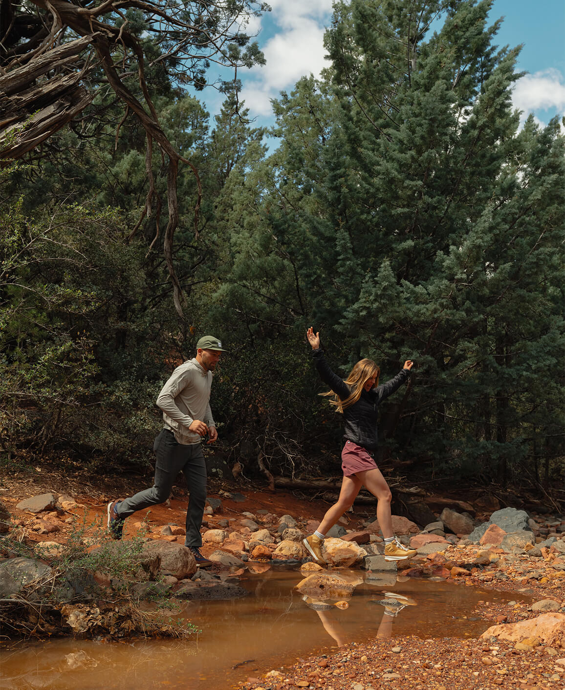 Image features a couple walking in the woods.